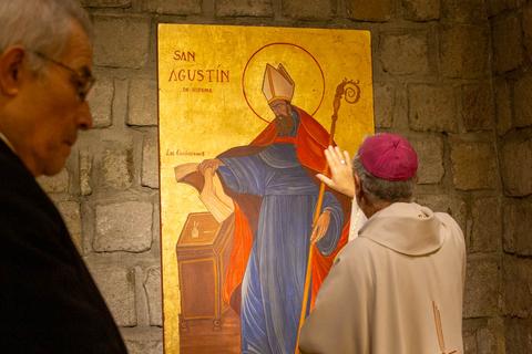 Un grupo de personas observa una pintura religiosa que representa a San Agustín.