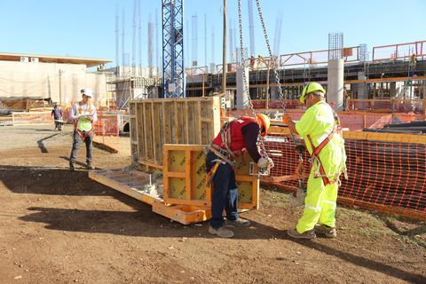 Trabajadores en una obra de construcción están manipulando un equipo de elevación.
