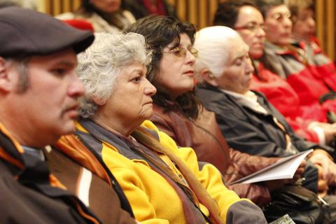 Un grupo de personas mayores escuchando atentamente en un evento.
