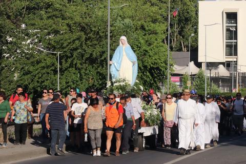 Una multitud participa en una procesión religiosa con una estatua de la Virgen María.