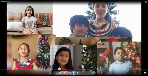 Un grupo de niños cantando alrededor de un árbol de Navidad decorado.