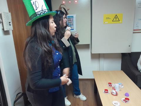 Dos personas están en una habitación, una de ellas lleva un sombrero verde y ambas parecen participar en una actividad lúdica.