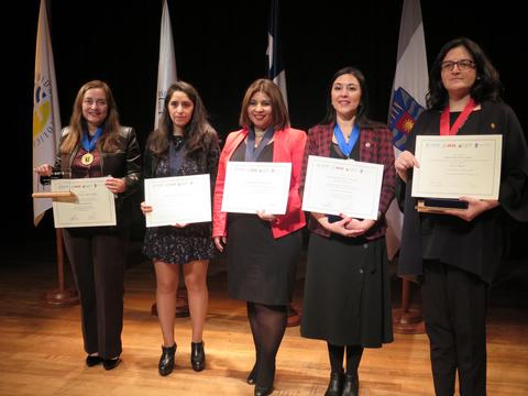 Un grupo de mujeres posan en un evento de premiación, sosteniendo certificados y medallas.