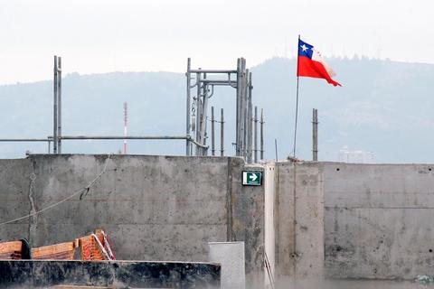Una bandera chilena ondea sobre una construcción en un paisaje urbano.