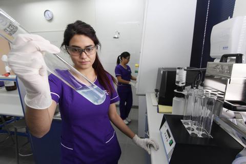 Una técnica de laboratorio sostiene un tubo de ensayo con líquido en un entorno de laboratorio.