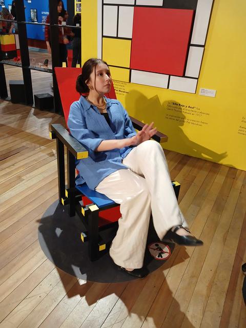 Una mujer sentada en una silla de diseño artístico en una exposición de arte.
