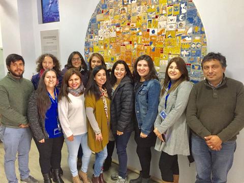 Un grupo de personas se posa frente a un mural colorido en una oficina.