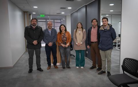 Un grupo de seis personas posando en un espacio de oficina moderno.