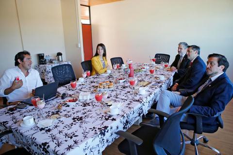 Una reunión formal en una sala con un grupo de personas sentadas alrededor de una mesa llena de comida y bebidas.
