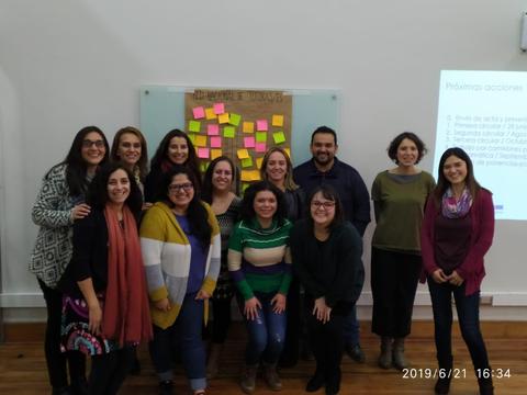 Un grupo de personas sonríe frente a una pizarra con notas adhesivas.