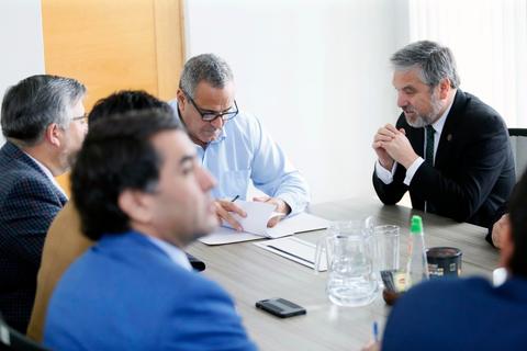 Un grupo de personas discutiendo alrededor de una mesa en un entorno de oficina.