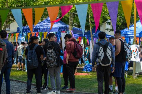 Grupo de jóvenes conversando en un evento al aire libre decorado con banderines de colores.