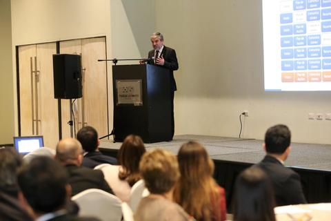 Un orador presenta en un evento frente a un público atento.