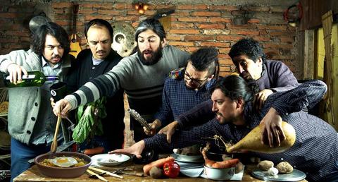 Un grupo de seis hombres se reúne para cocinar, mostrando entusiasmo y colaborando en la preparación de una comida tradicional.