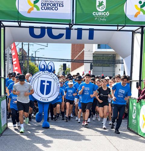 Un grupo de corredores con poleras azules atraviesan la meta en un evento deportivo en Curicó.
