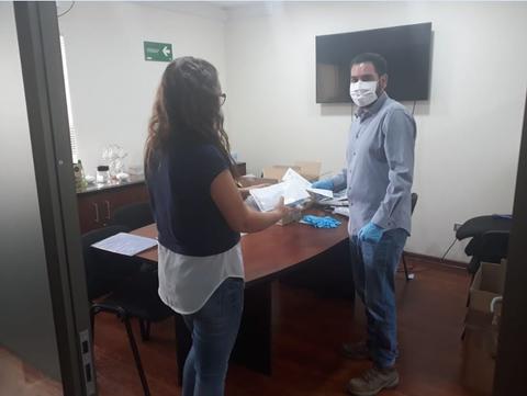 Dos personas intercambiando documentos en una oficina.