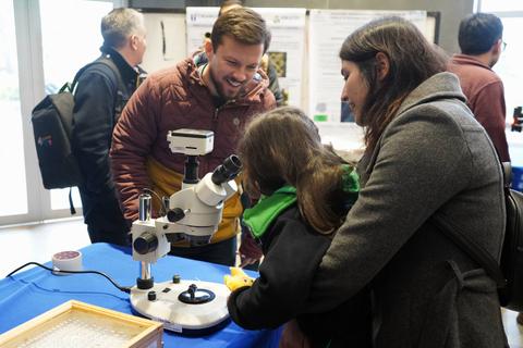 Una familia está disfrutando de una actividad educativa en la que observan a través de un microscopio.