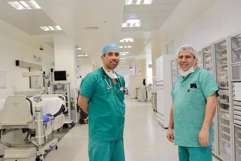 Dos médicos sonrientes en un pasillo de un hospital.