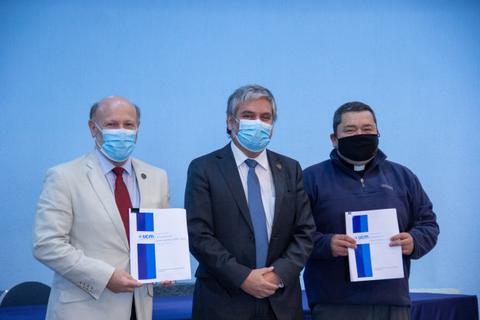 Tres hombres posan con documentos en un evento formal.