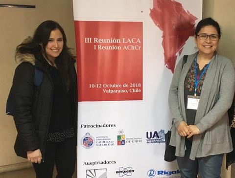 Dos mujeres posan frente a un cartel de la III Reunión LACA en Valparaíso, Chile.