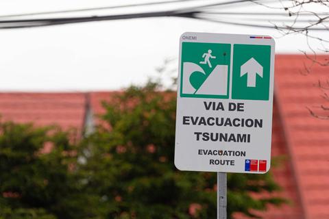 Se observa un letrero de ruta de evacuación para tsunamis en una zona residencial.