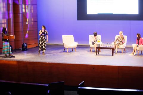 Un panel de discusión sobre un escenario con varias ponentes y un público atento.