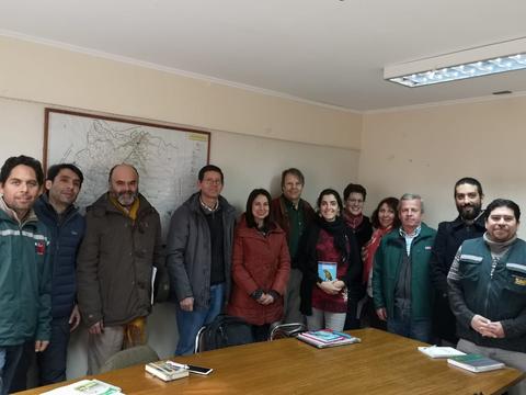 Un grupo de personas se reúne en una sala con un mapa en la pared.