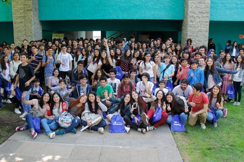 Un gran grupo de estudiantes posando juntos en un evento al aire libre.