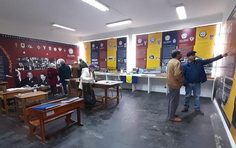 Una exposición en un museo donde varias personas observan fotografías y paneles informativos.