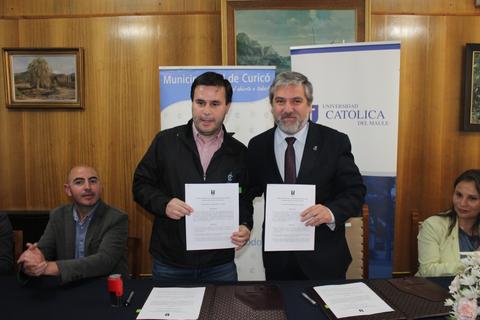 Dos hombres sostienen documentos en una reunión oficial.