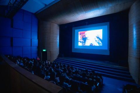 Una sala de cine llena de gente mirando una película proyectada en la pantalla.