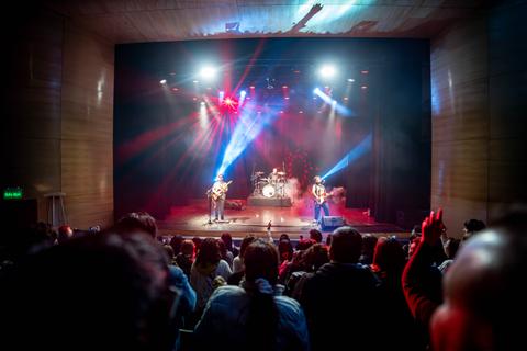 Un grupo de músicos está tocando en un escenario frente a un público entusiasta.