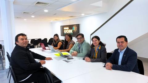 Un grupo de seis personas se reúne en una mesa para trabajar en un ambiente moderno.