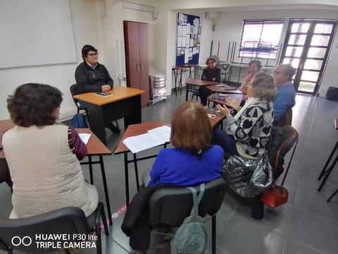 Un grupo de personas se encuentra en una sala de clases participando en una reunión o discusión.