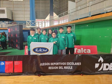 Un grupo de ocho jóvenes con chaquetas verdes posan en una competición deportiva escolar.