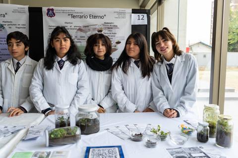Un grupo de estudiantes presenta su proyecto de terrario en una feria de ciencias.