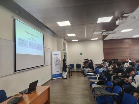 Una presentación en un salón de clases con varios estudiantes atentos.