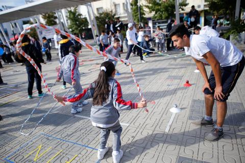 Un grupo de niños juega con una cuerda de saltar en una actividad al aire libre.