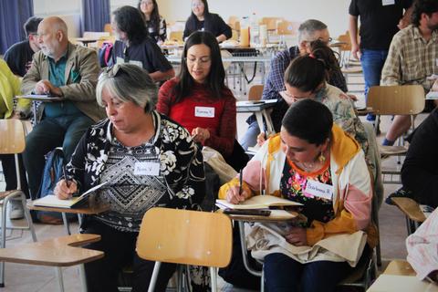 Un grupo de personas en una sala de clases, escribiendo y aprendiendo juntas.