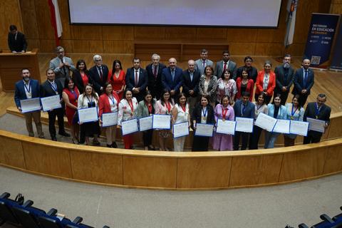 Un grupo de personas posa en un evento formal en Chile, sosteniendo certificados de reconocimiento.