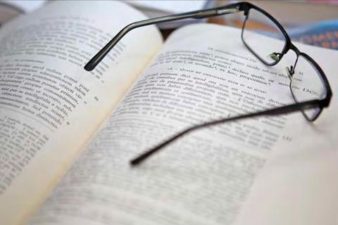 Unas gafas están descansando sobre un libro abierto lleno de texto.
