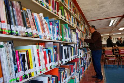 Un hombre mira libros en una estantería de una biblioteca.