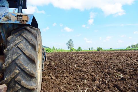 Una vista de un tractor en un campo de tierras cultivadas bajo un cielo despejado.