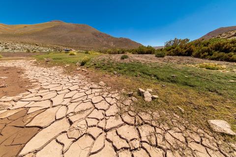 Un paisaje árido con suelos agrietados y montañas al fondo.