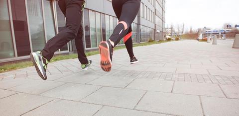 Dos personas corriendo por una vereda moderna.