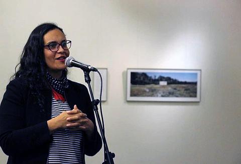 Una mujer habla en un micrófono durante un evento en una galería de arte.