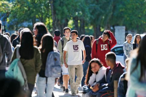 Un grupo de estudiantes camina por un claro entre árboles en una universidad.