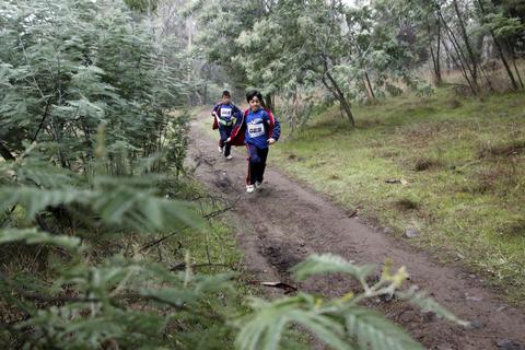 Un par de niños corren por un sendero en un bosque.