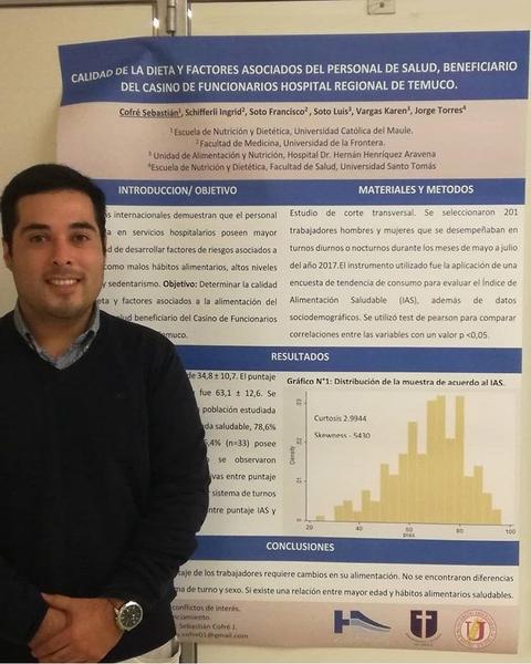 Un hombre sonriente posa junto a un póster de investigación sobre la calidad de la dieta del personal de salud en un hospital.