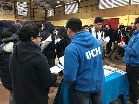 Un grupo de estudiantes interactúa en un evento educativo en un gimnasio.